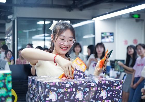 BESEN team member opening a gift at a company event, surrounded by colleagues.