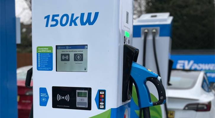 Close-up of a 150 kW DC fast charging station with a blue charging cable, displaying various user interface elements and payment options.