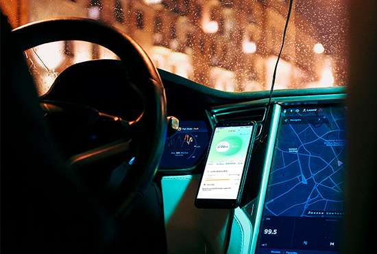 A smartphone mounted on a car dashboard, displaying a smart app integration for an electric vehicle charger.