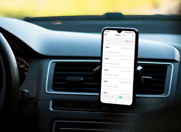 A smartphone mounted on a car dashboard displaying the charging history of an electric vehicle charger.