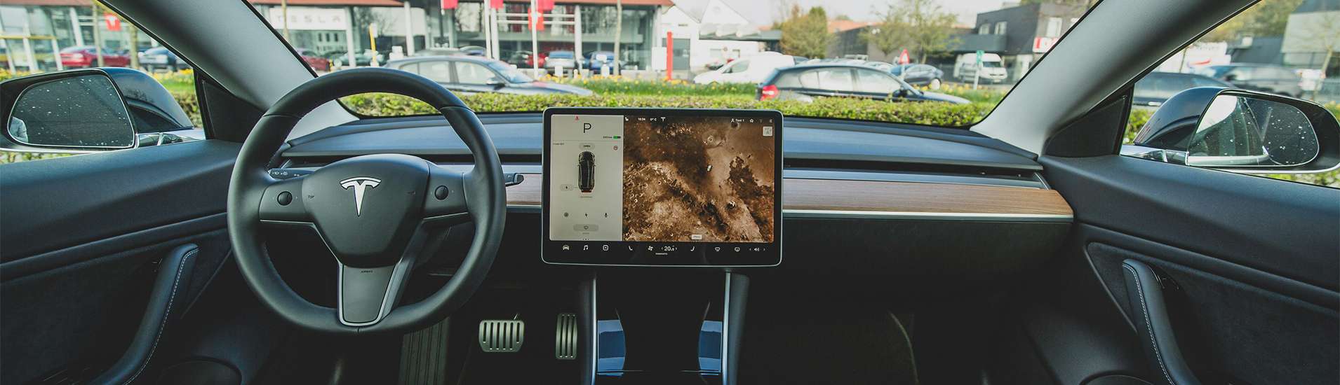 Interior view of a Tesla Model 3, showcasing the steering wheel, dashboard, and large central touchscreen display with charging information.