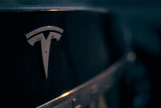 Close-up of Tesla logo on a car's exterior at night