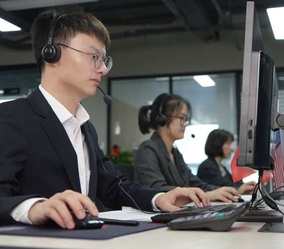 Members of the BESEN customer service team wearing headsets and working at their computers in an office setting.