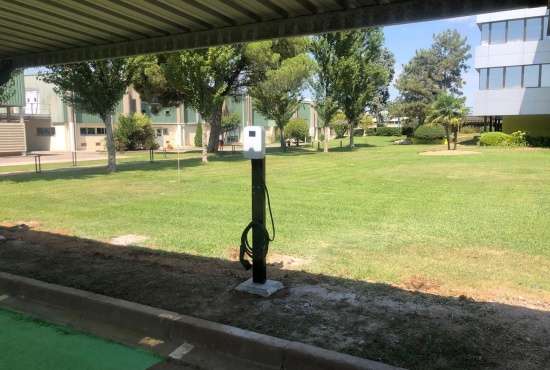 BESEN customized EV charging station installed in a hotel with a lush green lawn and modern buildings in the background.