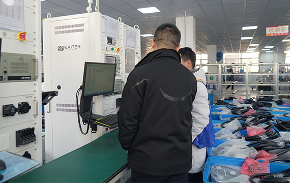 Two workers inspecting Besen J1772 EV chargers on a manufacturing line.