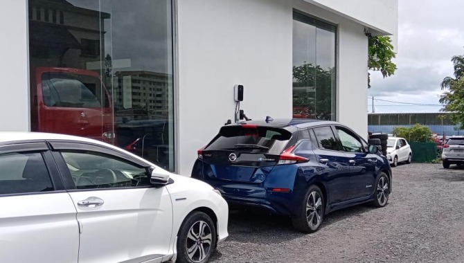 Two electric vehicles parked in front of a modern condominium with a visible BESEN EV charging station, demonstrating urban EV charging solutions.