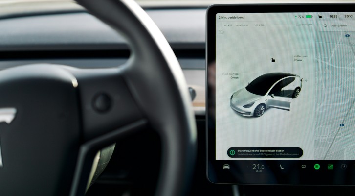 Interior view of a Tesla electric vehicle, showcasing the dashboard and large touchscreen displaying driving information.