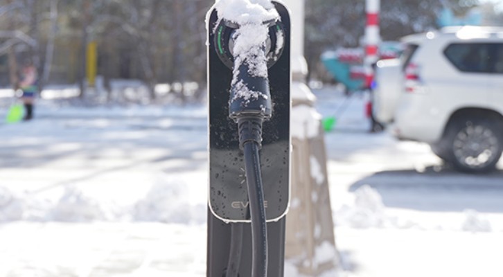 BESEN BS30 EV charging station providing charging for a Tesla electric vehicle in cold weather conditions, with snow visible around the station.