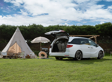 Electric vehicle parked near a tent at a vacation spot, illustrating the use of BESEN 40-amp portable EV chargers as a flexible secondary charging solution for multiple locations.