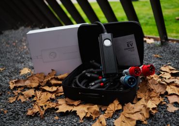 Portable BESEN EV charger in a carrying case, placed on fallen autumn leaves, showing cables and connectors ready for use.