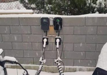 Two BESEN EV charging stations mounted on an outdoor wall in a snowy setting, with charging cables plugged in and ready for use.